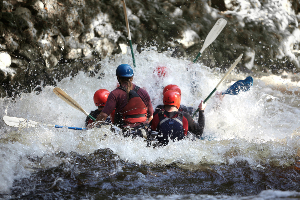 Pratique du rafting en eaux vives, groupe de voyageurs en pleine action avec gilets et casques de sécurité