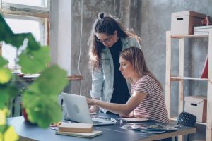 Sortir du régime micro-entreprise sans changer de statut. Deux personnes collaborant sur un ordinateur portable dans un espace de travail, en lien avec une évolution du régime fiscal d'une entreprise.