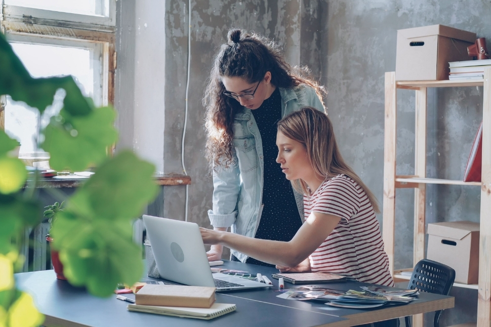 Sortir du régime micro-entreprise sans changer de statut. Deux personnes collaborant sur un ordinateur portable dans un espace de travail, en lien avec une évolution du régime fiscal d'une entreprise.